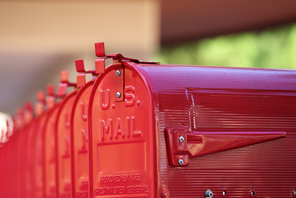 A row of red mail boxes sitting next to each other.