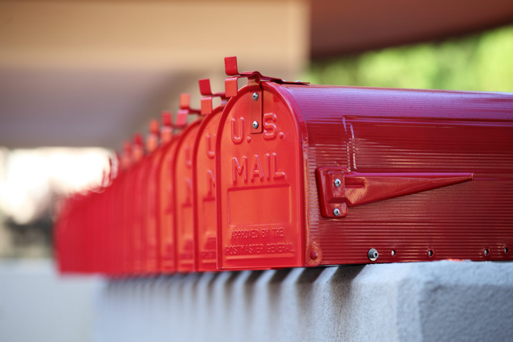 A row of red mailboxes sitting on top of a wall.